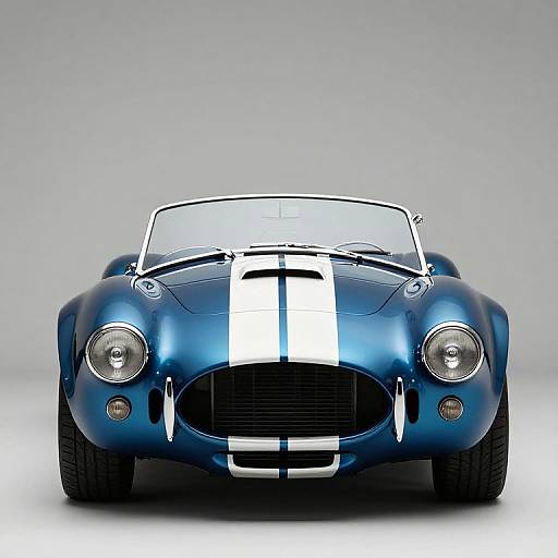 Photograph of a sleek, blue vintage convertible sports car with a white racing stripe, front view, gray background, round headlights, and chrome grill.