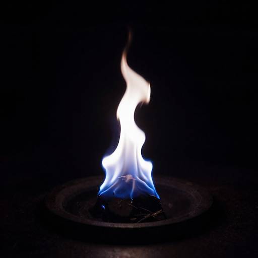 Photograph of a bright blue and white flame centered against a completely black background, with a circular metal grate at the base.
