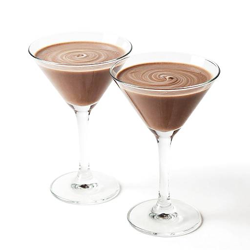Photograph of two glass martini glasses filled with creamy brown swirl-patterned chocolate drinks, set against a white background.