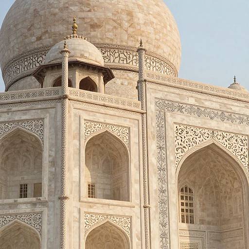 Photograph of a detailed Mughal-style marble building with a large dome, intricate arches, and lattice patterns, bathed in sunlight.