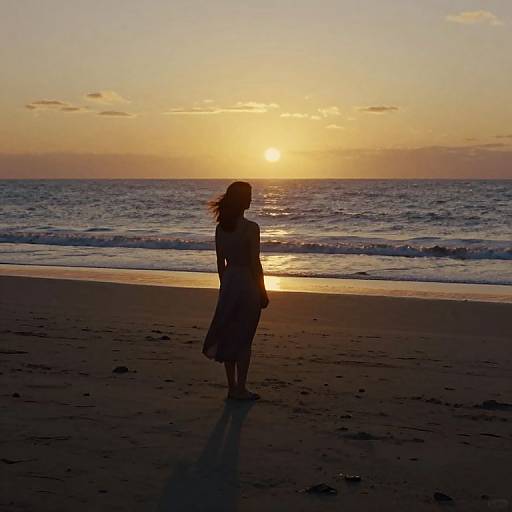 Silhouetted woman in a dress stands on a beach at sunset, ocean waves in background, golden sun reflecting on calm water.