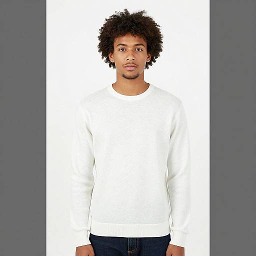 Photograph of a young Black man with curly hair, wearing a plain white long-sleeve shirt and dark blue jeans, standing against a white background