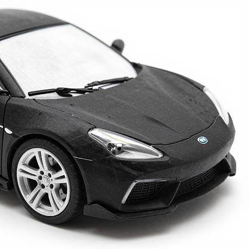 Photograph of a sleek, black Mini Cooper with shiny silver alloy wheels and sharp, angular headlights, set against a white background.