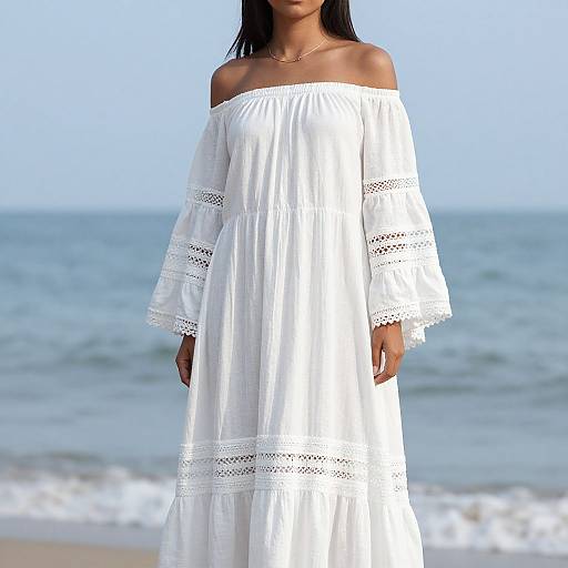 Photograph of a woman with dark skin and straight black hair, wearing an off-shoulder, white, lace-trimmed, long dress,