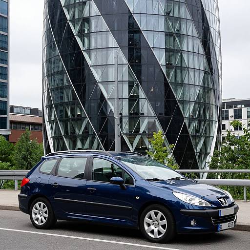 Photograph of a sleek, dark blue hatchback car parked in front of a modern, glass-and-steel building with geometric patterns. Urban setting with
