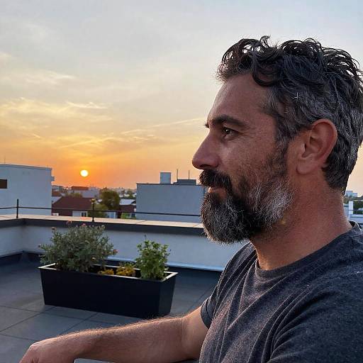 Man with salt and pepper beard on rooftop at sunset