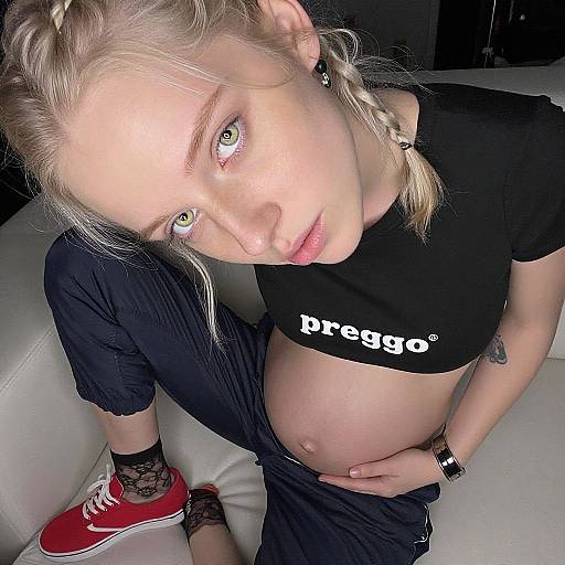 Photograph of a pregnant blonde woman with green eyes, black crop top, 