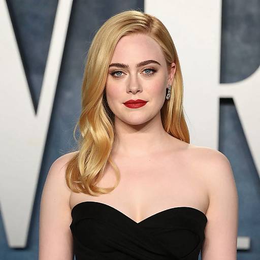 Photograph of a blonde woman with fair skin, red lipstick, and black strapless dress, standing against a dark blue background with large white letters.