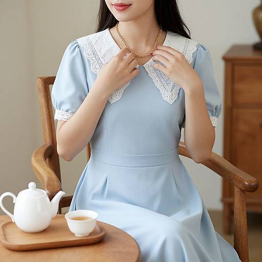 Photograph of an Asian woman with long black hair, wearing a light blue vintage dress with white lace collar, sitting in a wooden chair, holding a