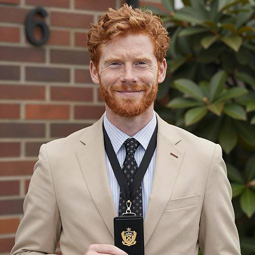 Smiling Redhead Man in Beige Suit Holding Badge