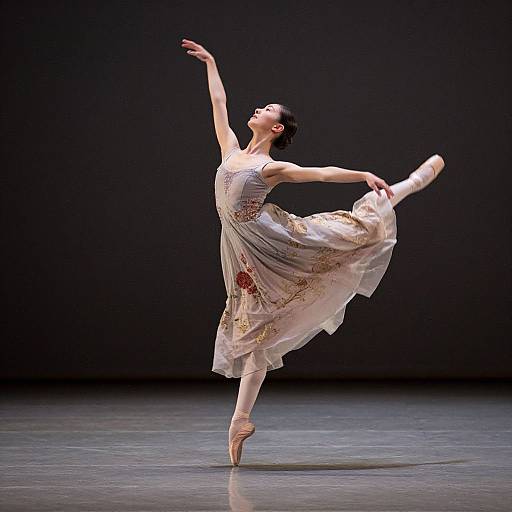 Photograph of a ballerina in a flowing, floral-patterned white dress, balancing on pointe, arms gracefully extended, performing on a dark