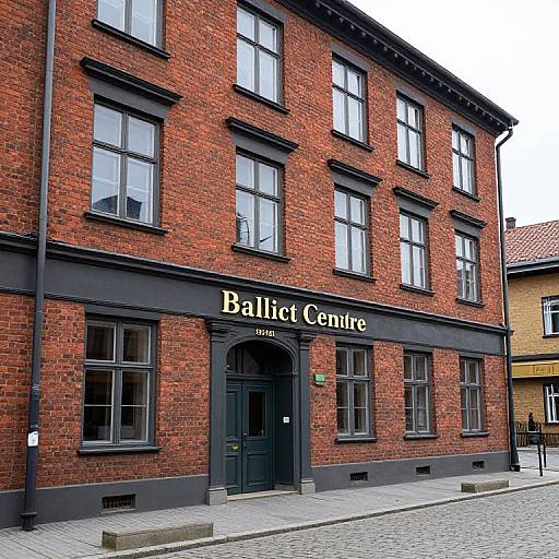 Photograph of a red-brick building with black-framed windows and a black sign reading 