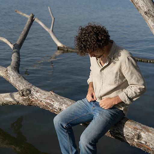 Man Sitting on Tree Branch Over Water