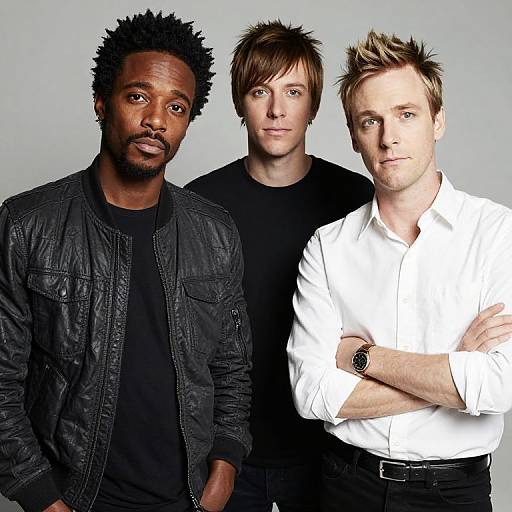 Photograph of three men: African-American with black jacket and shirt, light-brown haired in black shirt, and blonde-haired in white shirt, standing