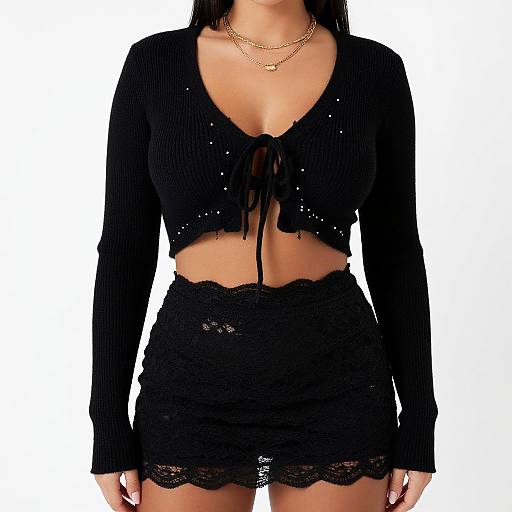 Photograph of a woman wearing a black, long-sleeve crop top with sequins and lace trim, paired with a black lace mini skirt,