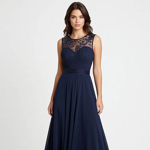 Photograph of a brunette woman with wavy hair, wearing a sleeveless, navy blue lace and chiffon evening gown, standing against a white background