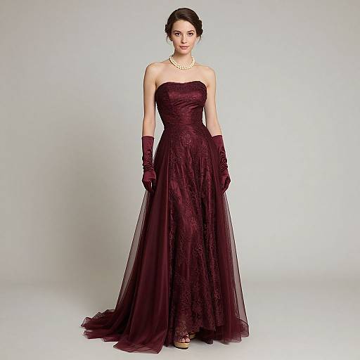 Photograph of a slender woman with pale skin and dark hair in an elegant, strapless, deep maroon lace gown and matching gloves, standing against