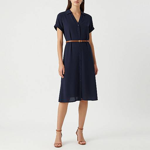 Photograph of a woman in a navy blue, short-sleeved, knee-length dress with a brown belt and brown high-heeled sandals, standing