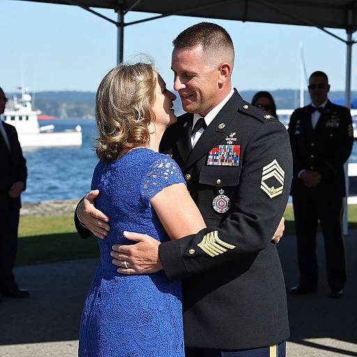 Photograph of a military officer in a black dress uniform, with medals, hugging a woman in a blue lace dress, under a tent by a