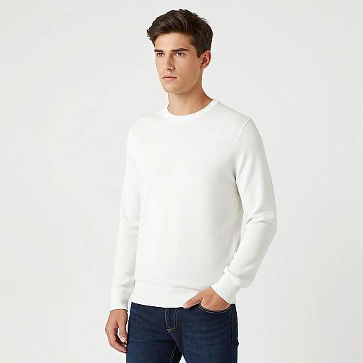 Photograph of a young, fair-skinned man with short dark brown hair, wearing a white long-sleeve shirt and dark blue jeans, standing