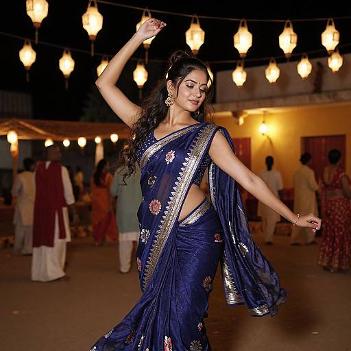 Photograph of an elegant Indian woman dancing at night, wearing a navy blue sari with silver and floral embroidery, under warm, glowing lanterns.