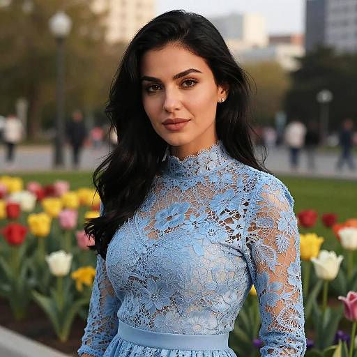 Photograph of a beautiful woman with long black hair, wearing a light blue lace dress, standing in a park with colorful tulips in the background.