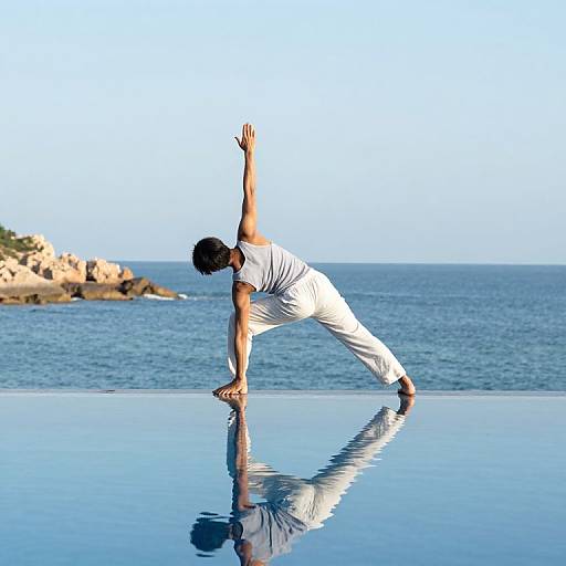 Photograph of a man in white yoga pants and shirt, performing a balance pose on an infinity pool, reflecting in water, with a clear blue ocean