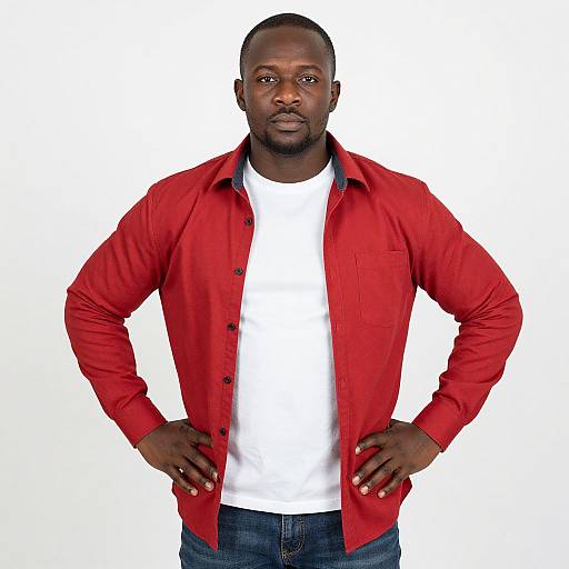 Photograph of a muscular, dark-skinned man with a bald head, wearing a red button-up shirt over a white t-shirt and blue jeans,
