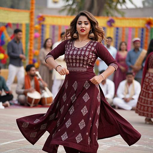 Photograph of a confident woman dancing in a maroon, diamond-patterned traditional dress, with vibrant festival decorations and spectators in the background.