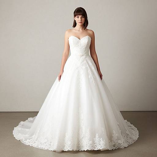 Photograph of a woman with black hair in a strapless, white lace wedding gown with a full, flared skirt, standing against a plain gray