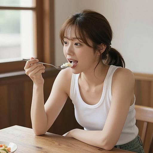 East Asian Woman Eating at Wooden Table