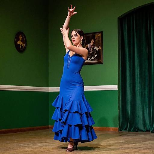 Photograph of a dark-haired woman in a blue, ruffled, strapless dress, dancing with arms raised, in a green-walled room with