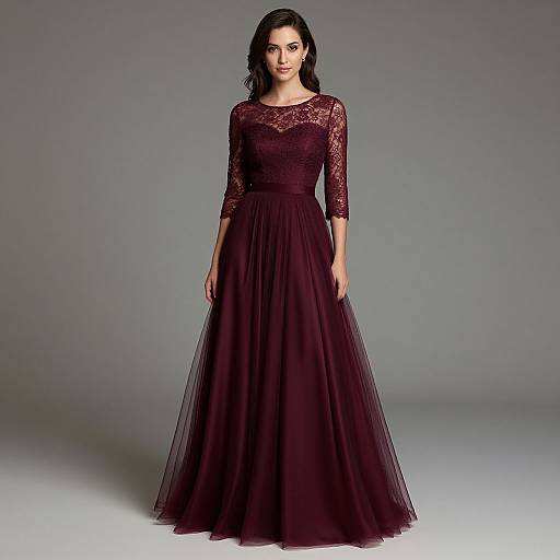 Photograph of a woman with dark hair wearing a full-length, deep burgundy lace dress with three-quarter sleeves, standing against a gray studio background.