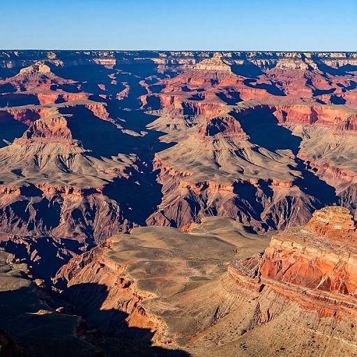 Photograph of the Grand Canyon at sunset, showcasing vibrant red and orange rock formations against a deep blue sky, with dark shadows creating a dramatic contrast.