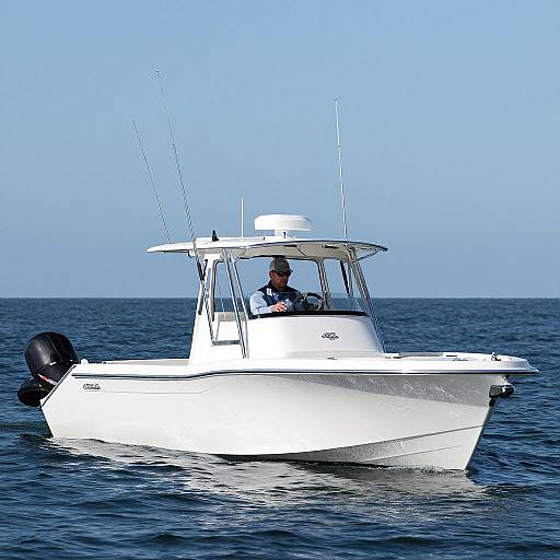 Photograph of a small white motorboat with a man in a blue shirt steering, on calm blue ocean waters under clear sky.