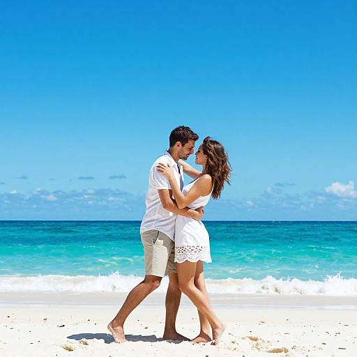 Photograph of a couple embracing on a sunny beach with turquoise water and clear blue sky. Man in white shirt and khaki shorts, woman in white