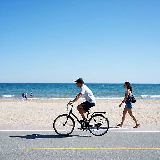 Photograph of a man in a white shirt and black shorts biking, with a woman in a black top and denim shorts walking beside him on a sunny