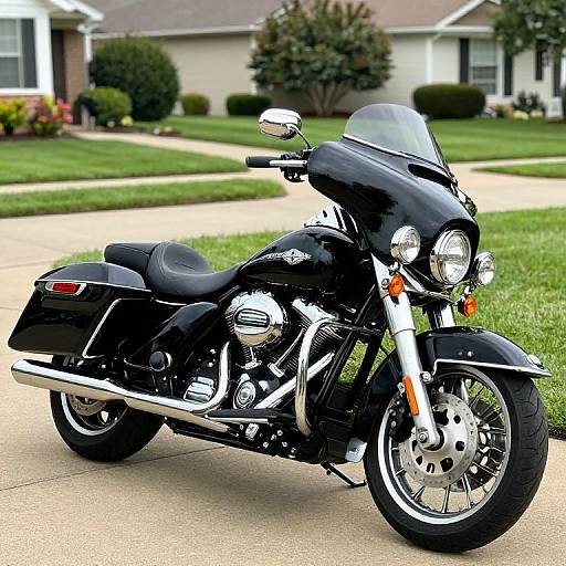 Photograph of a sleek black Harley-Davidson motorcycle with chrome accents, parked on a suburban concrete driveway, with a grassy yard and house in