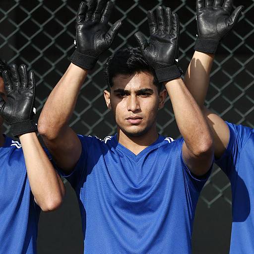 Three Men in Blue Jerseys Behind Fence