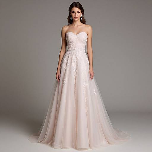 Photograph of a woman in a strapless, white, lace-embellished wedding gown with a sweetheart neckline and flowing tulle skirt, standing