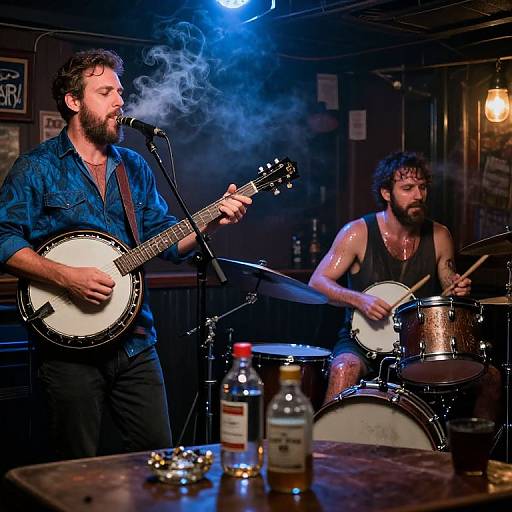 Photograph of two bearded men performing in a dimly lit bar; one plays banjo with smoke, the other drums, both in dark shirts