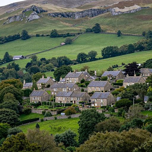 Photograph of a picturesque rural village with stone cottages nestled in lush green hills, surrounded by trees and rolling countryside.