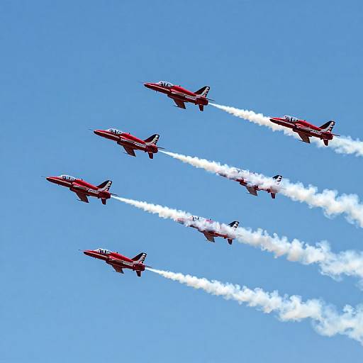 Photograph of five red aerobatic jets, trailing white smoke, performing a synchronized formation flight against a clear blue sky.