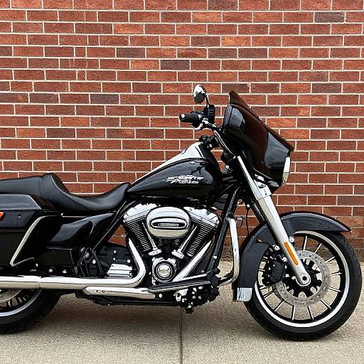 Photograph of a black and white Harley-Davidson motorcycle with chrome accents, parked against a red brick wall.