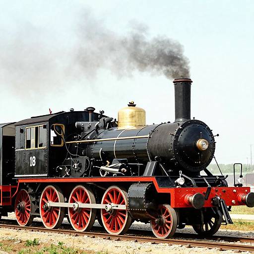 Photograph of a vintage black steam locomotive with red wheels and undercarriage, emitting black smoke, numbered 18, on railway tracks.