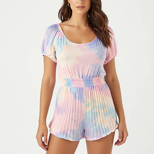 Photograph of a woman with long brown hair wearing a pastel tie-dye short-sleeve romper with a scoop neckline, against a white