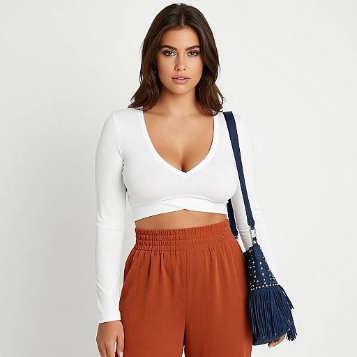 Photograph of a brunette woman with medium skin tone, wearing a white V-neck crop top, high-waisted orange pants, and a blue fringe