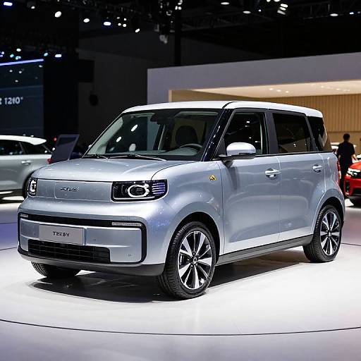 Photograph of a silver Mini Countryman SUV on a brightly lit exhibition floor, with other cars and a blurred audience in the background.