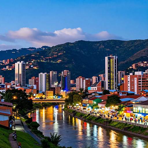 Vibrant cityscape photograph at dusk, featuring illuminated skyscrapers and red-brick buildings along a reflective river, with a crowd on a rivers