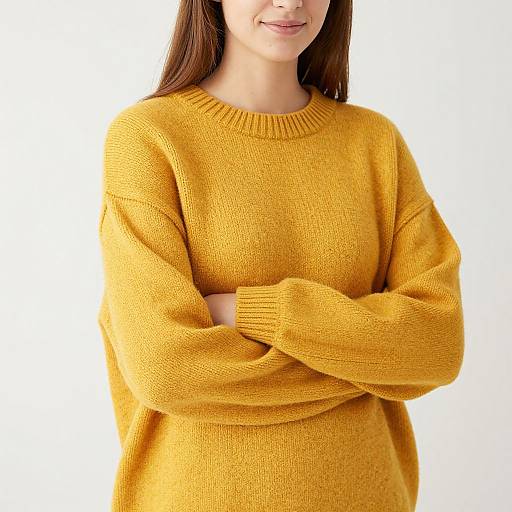 Photograph of a smiling woman with straight brown hair, wearing a bright yellow knitted sweater, arms crossed, against a plain white background.
